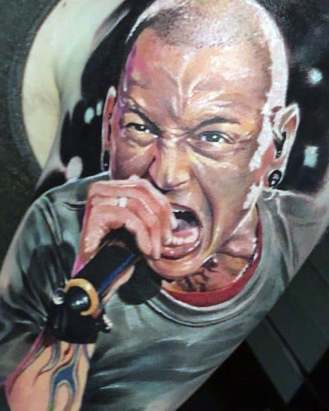 Hyper-realistic color tattoo of Chester Bennington passionately singing, with vivid details capturing his intense energy and expression.