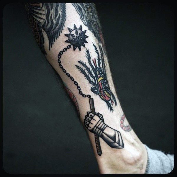 Bold black ink mace tattoo featuring a spiked ball on a chain, held by an armored hand, symbolizing strength, battle, and medieval power.
