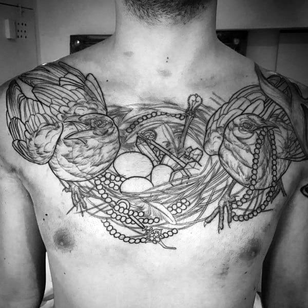 Black and gray chest tattoo featuring two magpies surrounding a nest with eggs, keys, and pearls, symbolizing protection, wealth, and mystery.