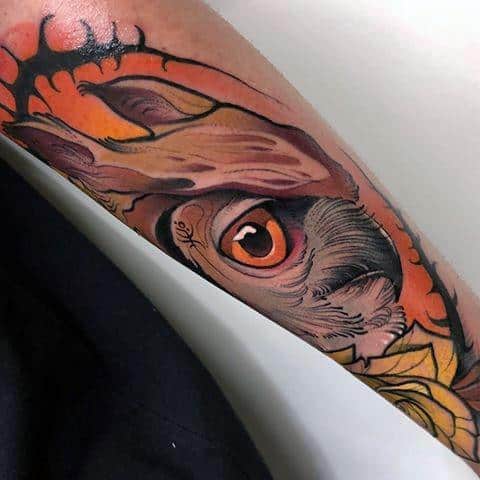 Neo-traditional owl tattoo with a striking eye, bold shading, and warm tones, creating an intense and detailed design on the forearm.