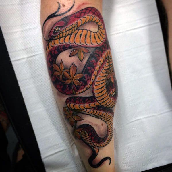 Neo-traditional tattoo of a coiled snake with bold red and gold scales, surrounded by delicate floral accents, creating a striking design.