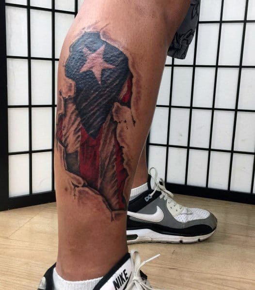 Puerto Rican flag tattoo with a ripped skin effect on the leg, revealing bold red, white, and blue colors with a striking star design.