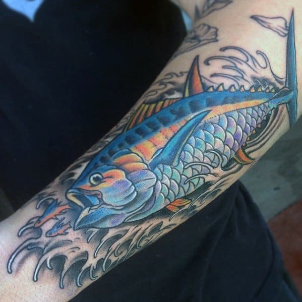 Vibrant tuna fish tattoo on a man's forearm, featuring bold colors, dynamic waves, and intricate details for a striking ocean-themed design.