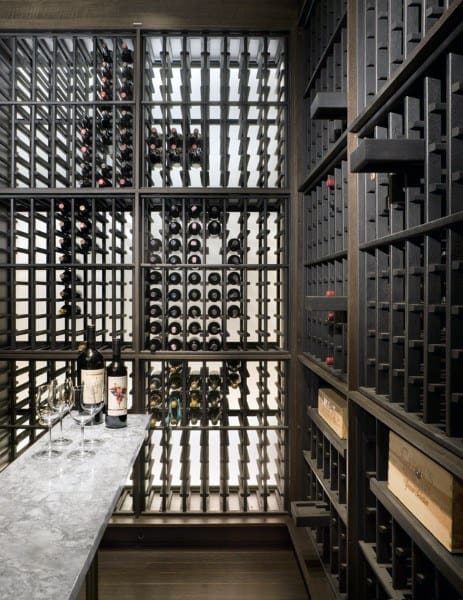 A wine cellar with bottles on racks, featuring a marble-topped table with wine bottles and glasses in the foreground