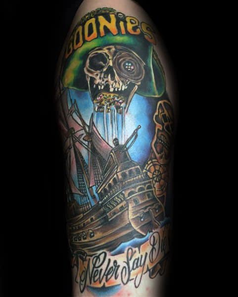 Colorful tattoo of One-Eyed Willy from The Goonies with a pirate ship, treasure, and the phrases "Goonies" and "Never Say Die" in bold lettering.