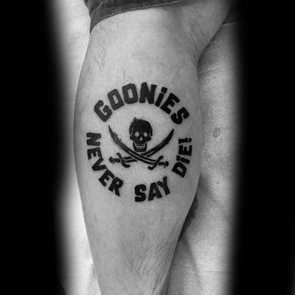 Black and gray tattoo of The Goonies featuring a skull and crossed swords with the phrase "Goonies Never Say Die!" in bold lettering.