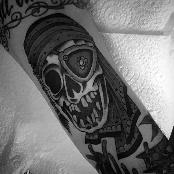 Black and gray tattoo of One-Eyed Willy from The Goonies, featuring a stylized skull with an eye patch, bandana, and bold shading details.