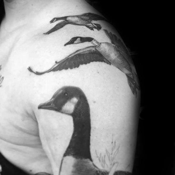 Black and gray tattoo of geese in flight and a detailed goose portrait, inked on the shoulder and upper arm in a realistic style.