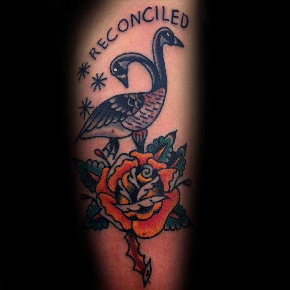 Traditional-style tattoo of two geese forming a heart shape above a vibrant yellow rose, with the word "RECONCILED" arched above them.