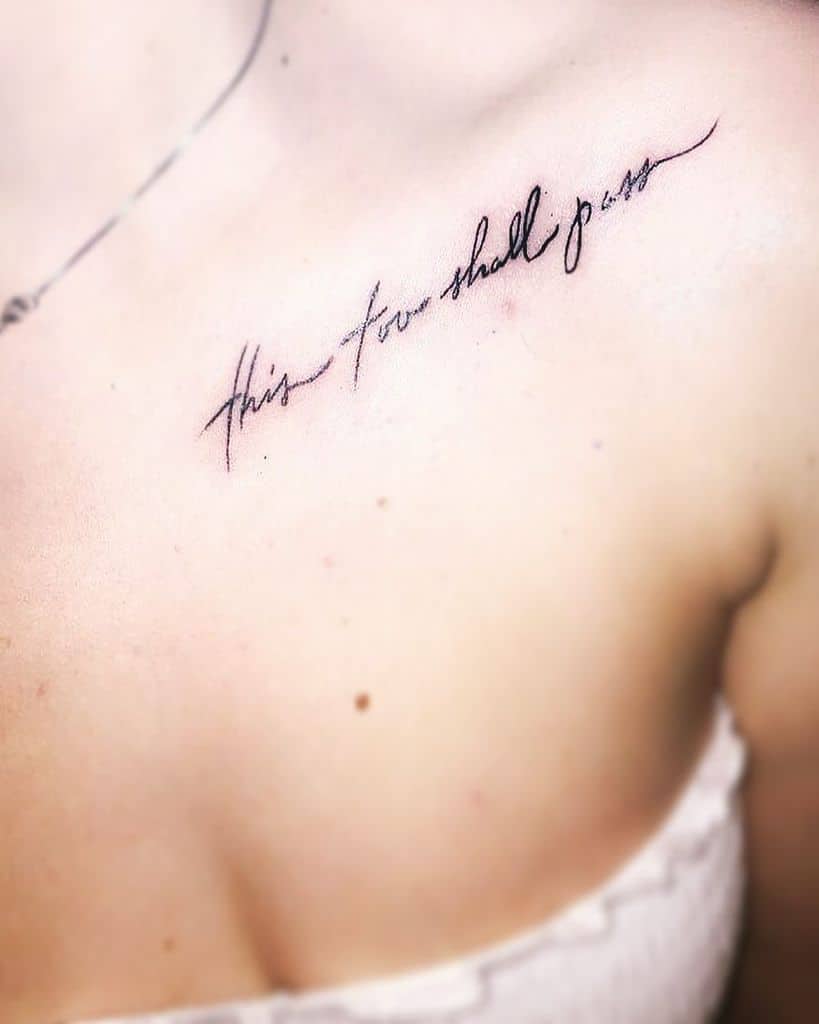 A "This Too Shall Pass" tattoo in cursive on the collarbone area.
