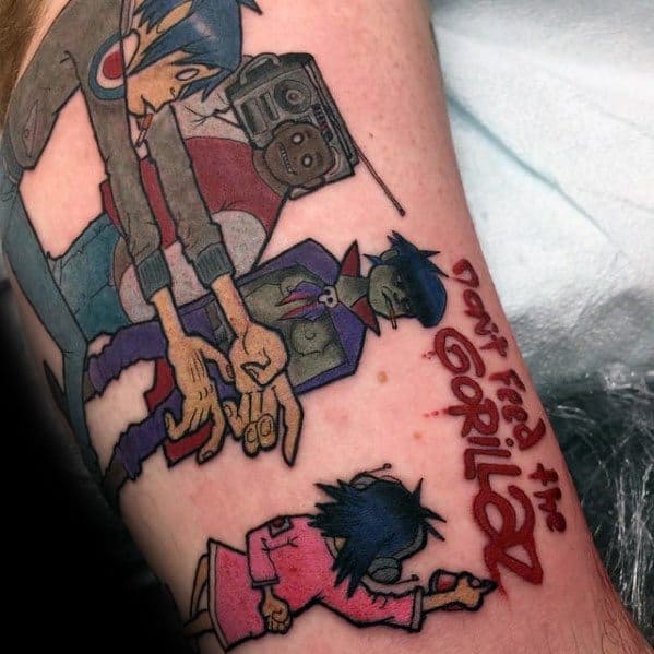 Colorful forearm tattoo of all Gorillaz band members with the phrase “Don’t Feed the Gorillaz” in bold red lettering beside them.