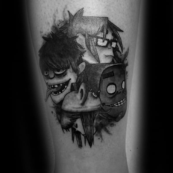 Black and grey tattoo of all four Gorillaz band members' heads, clustered together with splatter shading for a bold, grungy effect.