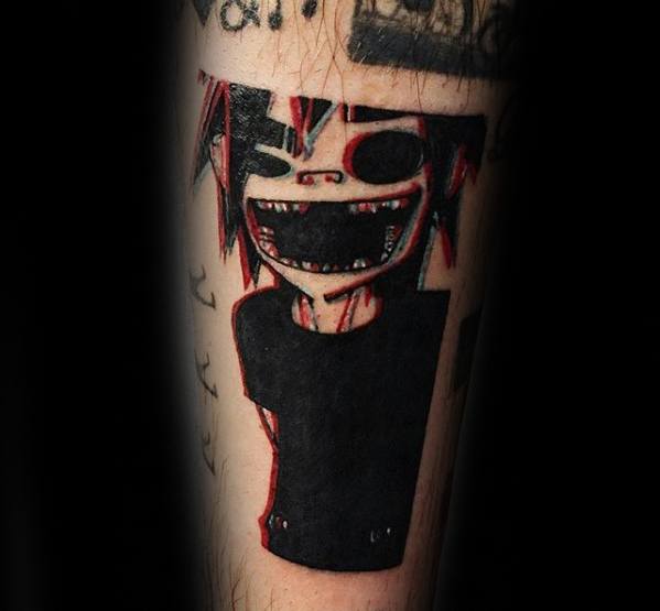 Dark and bold tattoo of Murdoc from Gorillaz with a wide grin, blacked-out shirt, and red accents creating a glitch-style effect.