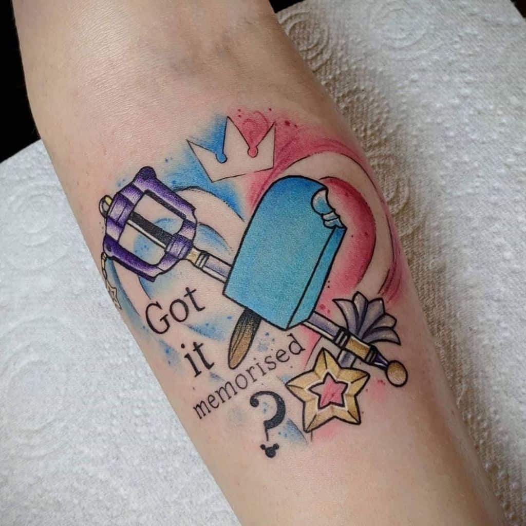 Colorful Kingdom Hearts tattoo featuring a Keyblade, sea-salt ice cream, Wayfinder charm, and 'Got it memorised?' text with a vibrant design.