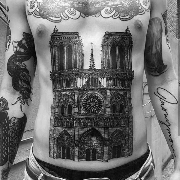 Black and grey chest and stomach tattoo featuring a highly detailed Notre-Dame Cathedral, showcasing intricate gothic architecture and fine linework.