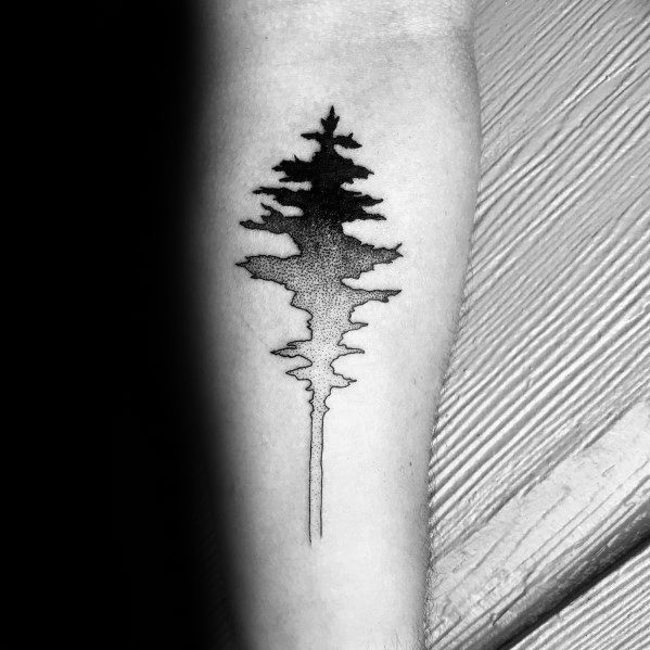 Black and grey gradient tattoo of a pine tree with mirrored reflection, fading into soft dotwork on the forearm.