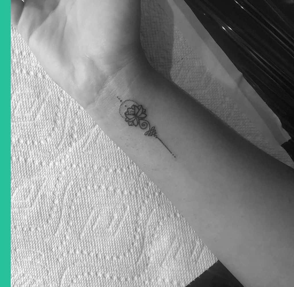 Delicate Unalome tattoo with a lotus on the wrist, symbolizing spiritual enlightenment, growth, and the journey toward inner peace.