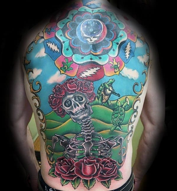 Colorful Grateful Dead full back tattoo featuring a skeleton with roses, dancing turtles, rolling hills, and iconic band symbols in the sky.