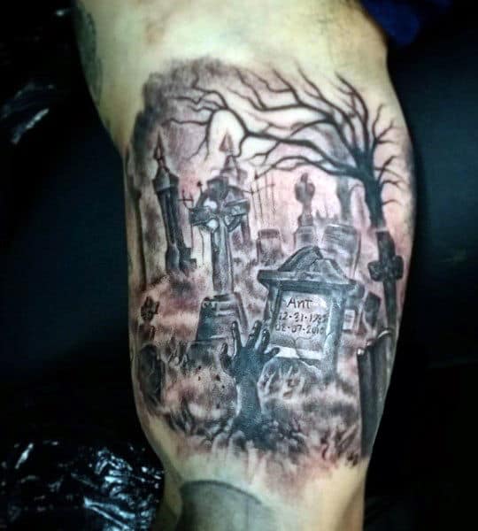 Graveyard tattoo with headstones, crosses, gnarled tree, and skeletal hand reaching from ground