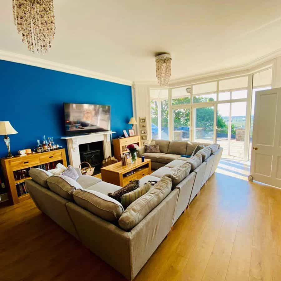 Bright living room with grey sectional, blue accent wall, and wooden furniture.