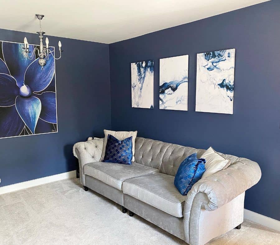Sophisticated living room with grey tufted sofa, blue accent wall, and abstract wall art.