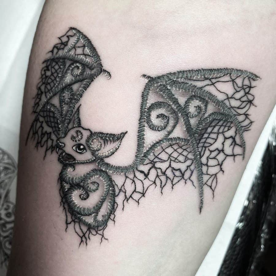 Intricate lace-inspired bat tattoo with fine embroidery details, giving it a delicate and artistic appearance.