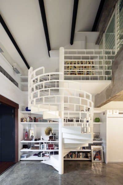 Modern loft with white spiral staircase, built-in shelving, and exposed beam ceiling.