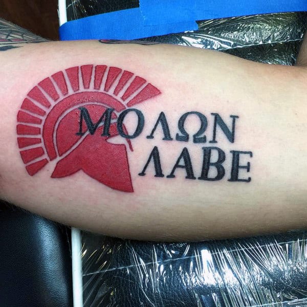 Greek Helmet In Red Ink With Molon Labe Words Tattoo On Bicep Of Man