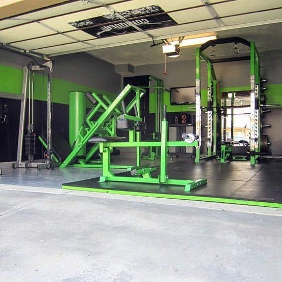 Garage gym with green and black equipment, power rack, leg press, and cable machine.