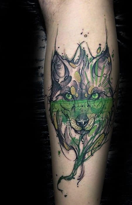 Artistic wolf tattoo with vivid green eyes and abstract green ink swirls, combining sketch-style lines and watercolor elements.