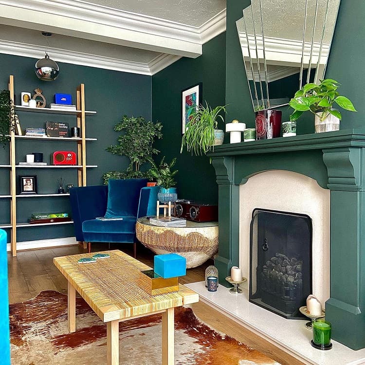 green wall fireplace surround wall mirror shelves blue accent table plants