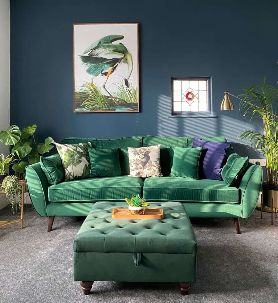 Stylish living room with green velvet sofa, botanical decor, and blue accent wall.