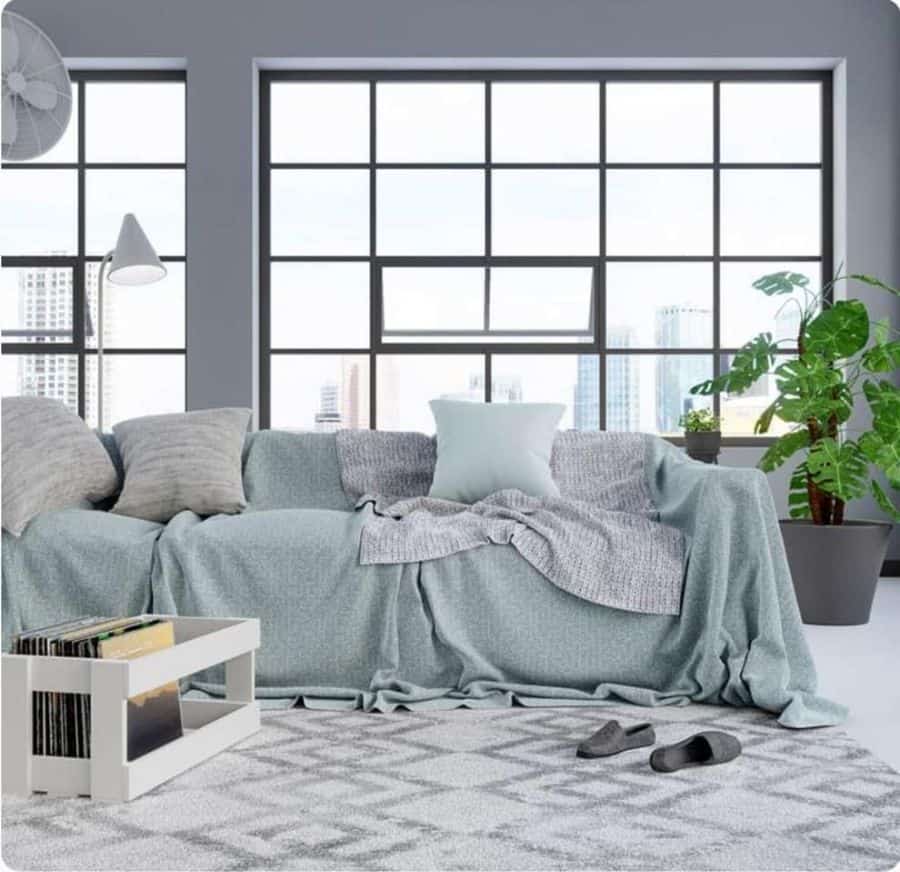 Bright living room with large windows, cozy grey sofa, and geometric patterned rug.