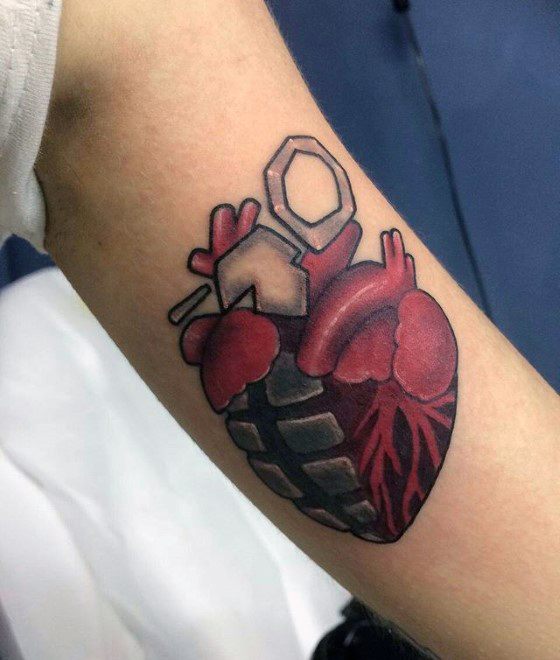 Tattoo of an anatomical heart shaped like a grenade, blending realism with punk style in tribute to Green Day’s *American Idiot* icon.
