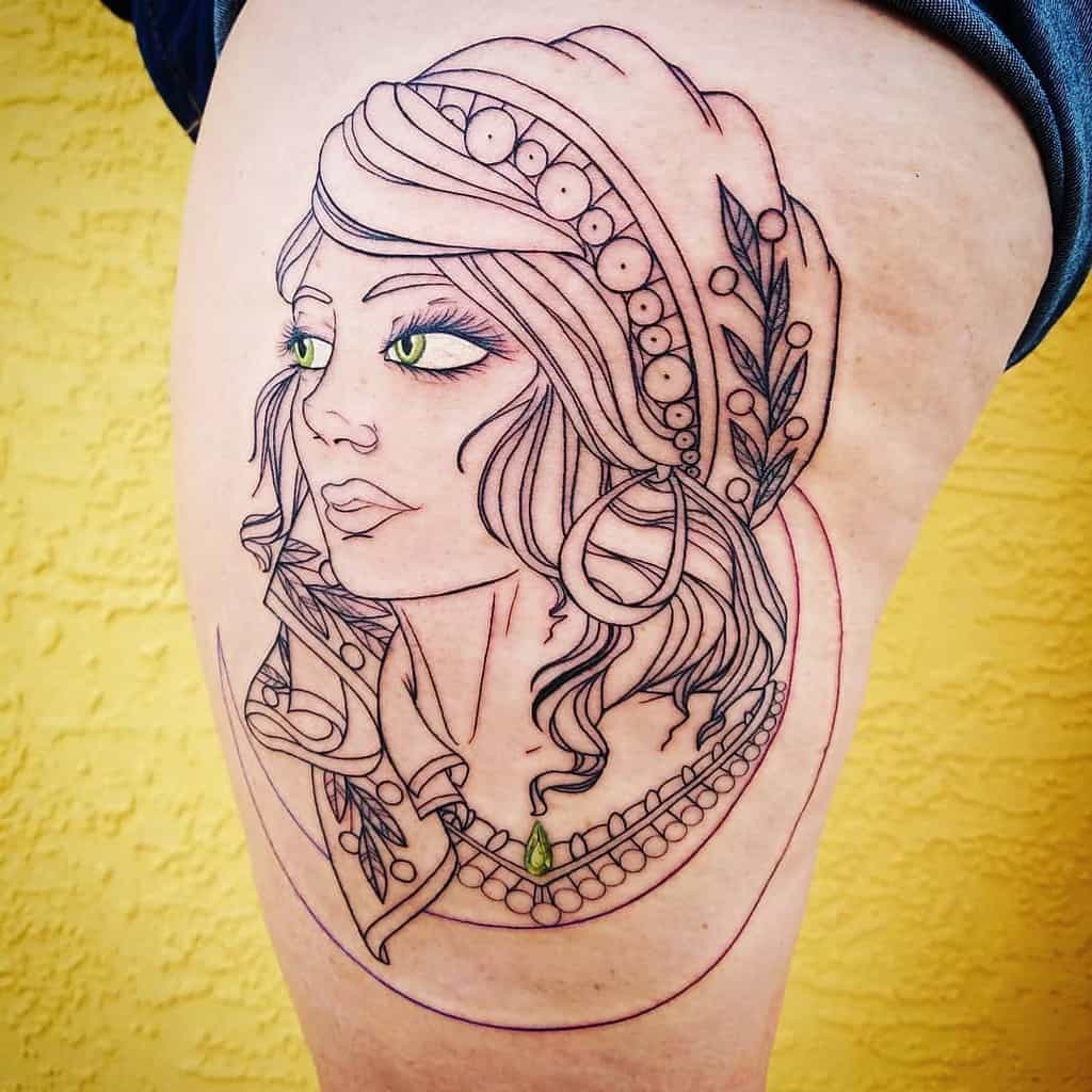 Fine line tattoo of a gypsy woman with a detailed headscarf, jewelry, and striking green eyes, placed on the thigh.