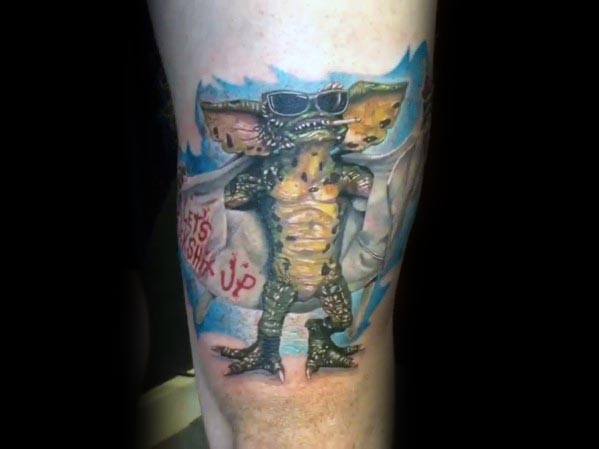 Gremlin tattoo with sunglasses and an open trench coat, striking a bold pose with a mischievous attitude and vibrant shading.