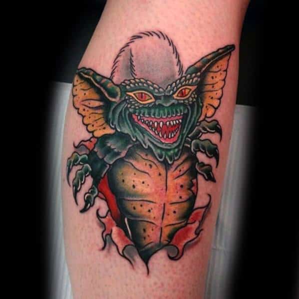 Gremlin tattoo with sharp claws, glowing red eyes, and a ripped-skin effect, creating a bold and menacing design.