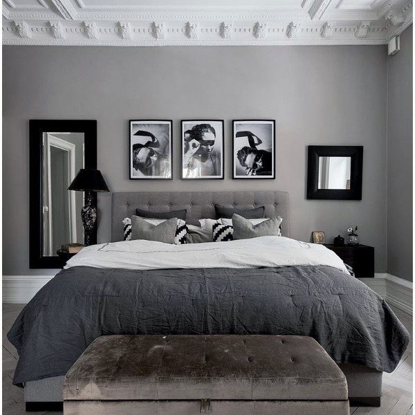 Modern bedroom with a grey theme, featuring a large bed, framed photos, and decorative moldings on the ceiling