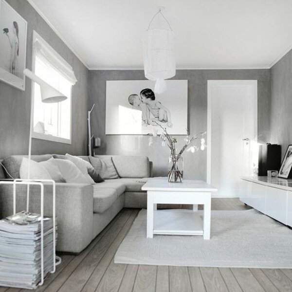 Small grey and white living room with a cozy sectional sofa, white coffee table, and soft decor.