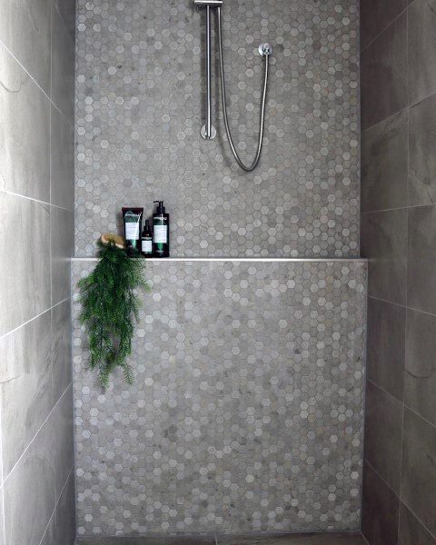 Light grey hexagonal tile shower with built-in shelf and minimalist showerhead.