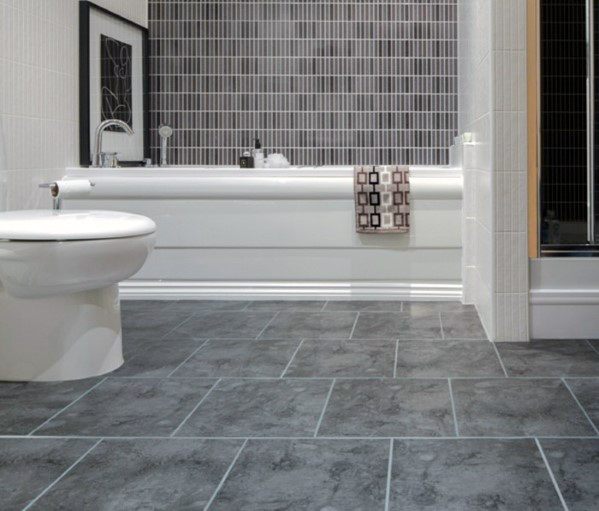 Gray tiled floor bathroom with white tub and vertical gray mosaic tile accent wall.