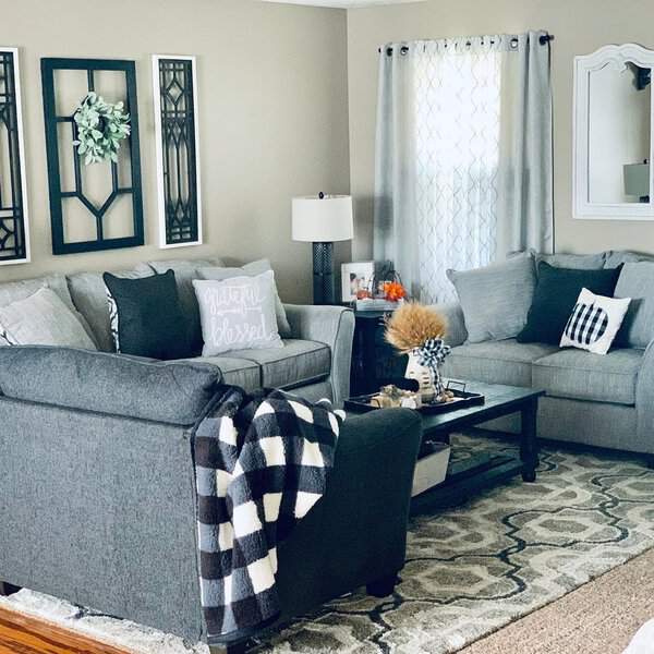 Grey and white living room with cozy seating, patterned pillows, and rustic DIY wall decor.