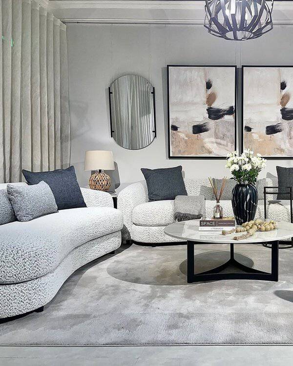 Grey and white living room with timeless design, curved sofas, abstract art, and modern decor.
