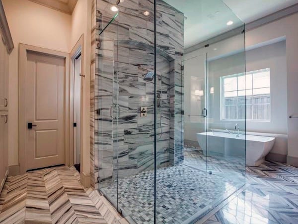 Luxury bathroom with grey and white marble shower, glass enclosure, and freestanding tub.