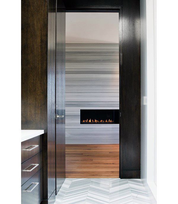 Sleek linear fireplace with gray striped wall, dark wood frame, and modern interior design.