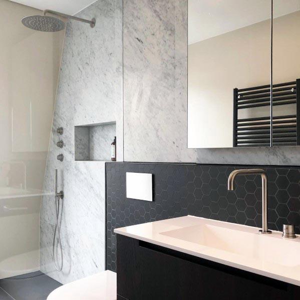 Modern grey bathroom with hexagon tile accents, marble walls, and sleek black cabinetry.