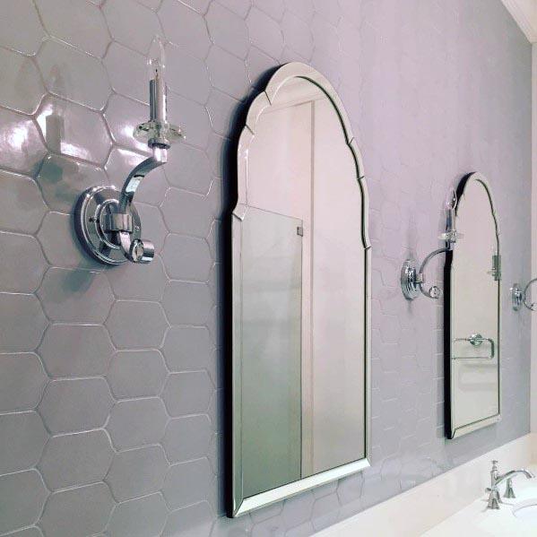 Elegant grey bathroom featuring hexagonal wall tiles, ornate mirrors, and chrome fixtures.
