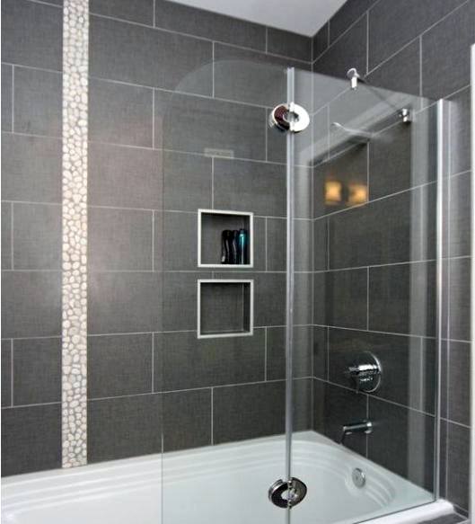 Bathtub with dark grey tiles, pebble stripe accent, and built-in shower niche shelves.