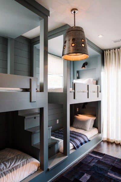 Bunk beds with wood paneling and a rustic hanging light, in a cozy, modern room