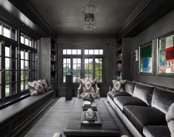 Sleek black man cave with a modern sofa, patterned chairs, bookshelves, and large windows